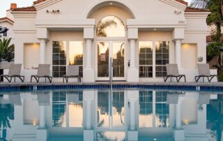 Luxury house with a swimming pool and reflection of the house in the water.