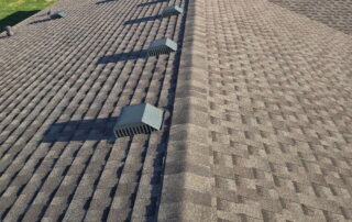View of a new asphalt shingle roof with installed roof vents in a rural area.
