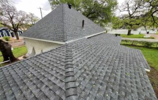 View of a residential roof with new asphalt shingles and a gutter system.