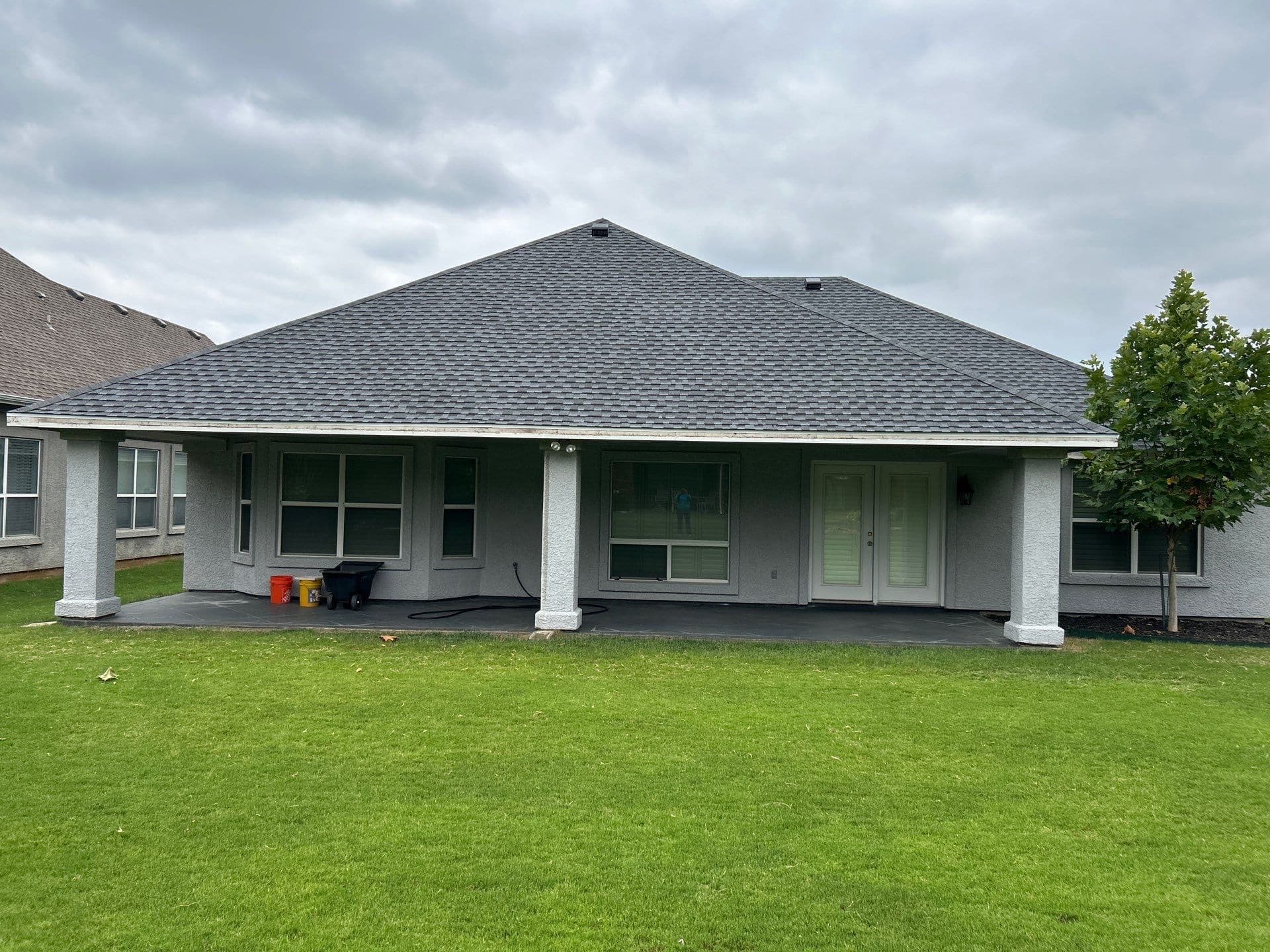 Back view of a house with a new shingle roof and a covered patio in Denton, TX.